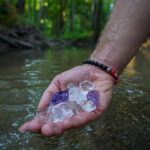 kryształy trzymane na dłoni w rzece Litoterapia-naturopatia