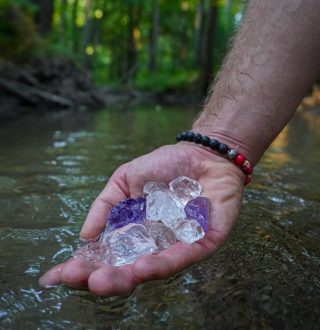 kryształy trzymane na dłoni w rzece Litoterapia-naturopatia
